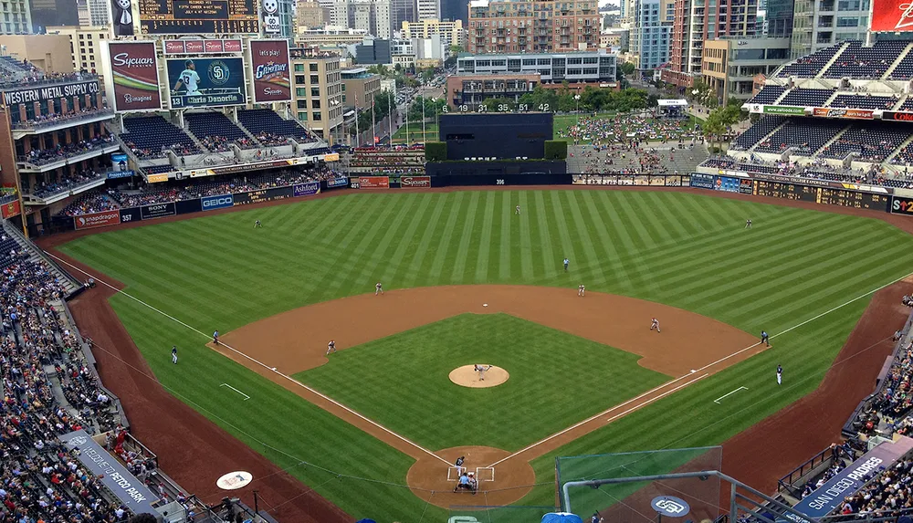 A baseball game is underway at a large open-air stadium with a city skyline in the background