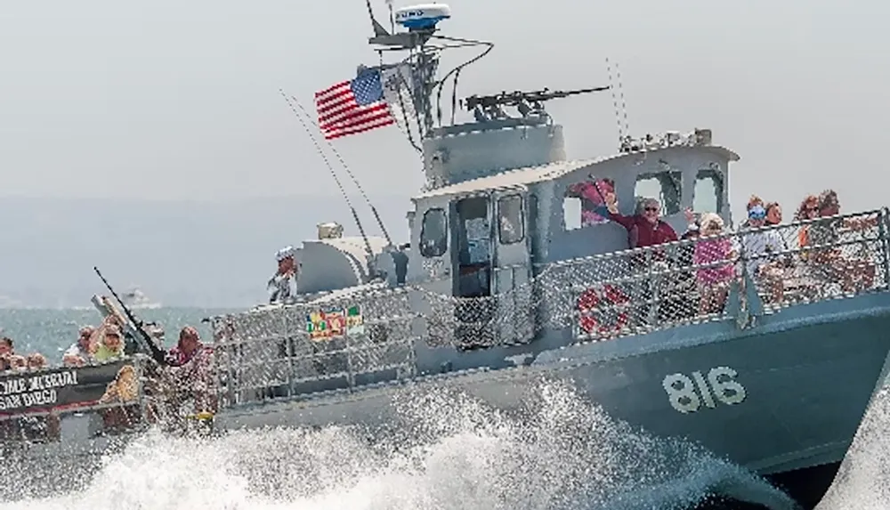 A military-style boat with the number 816 and an American flag navigates through choppy waters carrying people on board