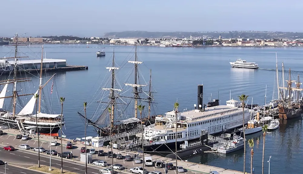 The image shows a scenic harbor with historic ships docked along the waterfront surrounded by city buildings and boats on the water