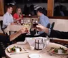 A couple is toasting with wine glasses at a nighttime outdoor setting with a plated dish of food inset in the image