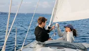 Two people are enjoying drinks while sailing on a boat.