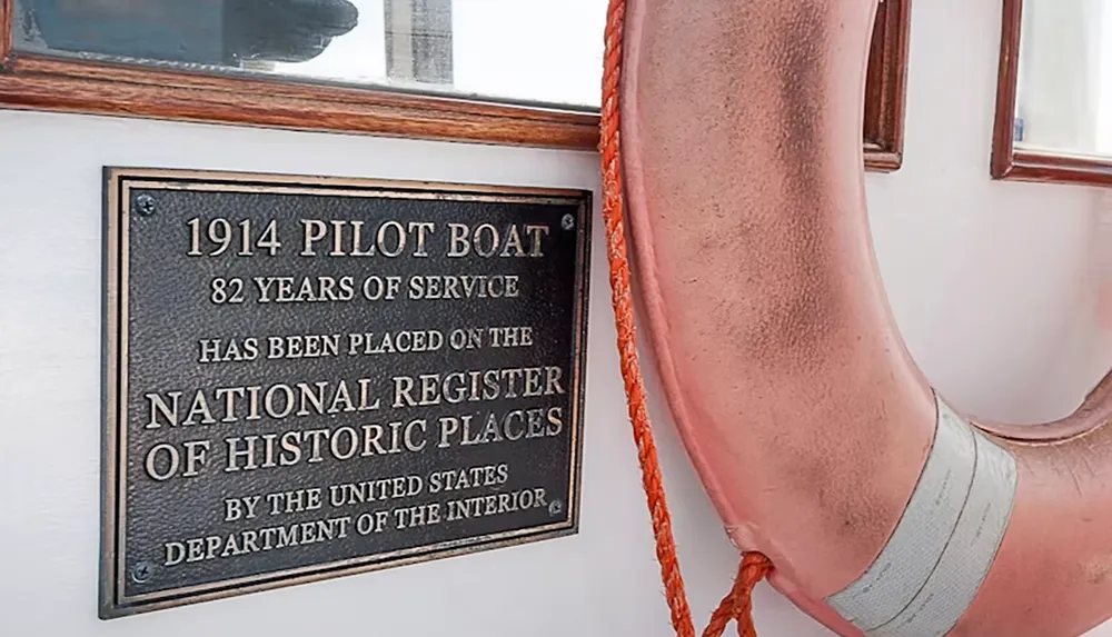 The image shows a plaque that recognizes a 1914 pilot boat for 82 years of service on the National Register of Historic Places alongside a life preserver