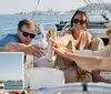 A group of people is enjoying drinks and smiling on a sailboat under sunny skies