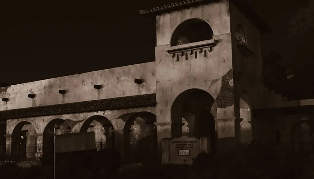 The image shows an old dimly lit building with arched doorways and a tower creating a mysterious and historic atmosphere