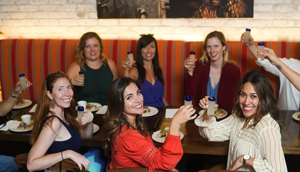 A group of women sitting at a restaurant table smiling and raising their glasses in a toast