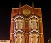 A group of people is gathered outside an ornate multi-story Victorian-style building at dusk