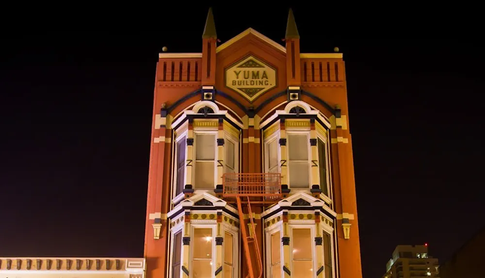 The image shows a brightly lit ornate building with a sign reading Yuma Building against a dark night sky