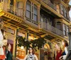 A group of people is gathered outside an ornate multi-story Victorian-style building at dusk