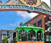 A city tour trolley passes under the Historic Heart of San Diego arch in a vibrant urban setting