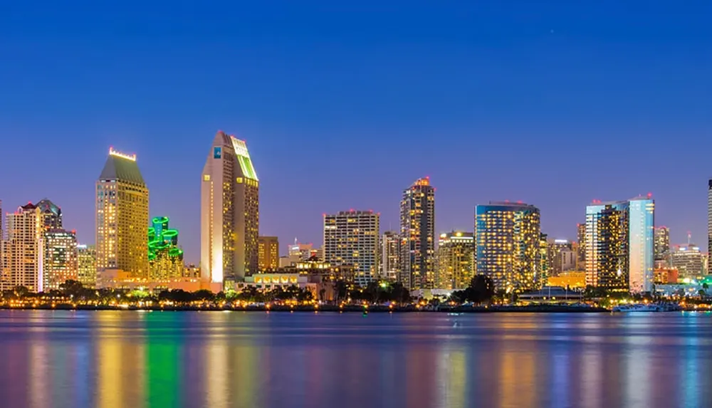 The image shows a vibrant city skyline at dusk with illuminated buildings reflecting on the water