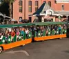 A group of people is riding a tour trolley in a town with historic-looking buildings in the background