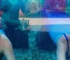 Two children are looking at a woman dressed as a mermaid inside an aquarium display