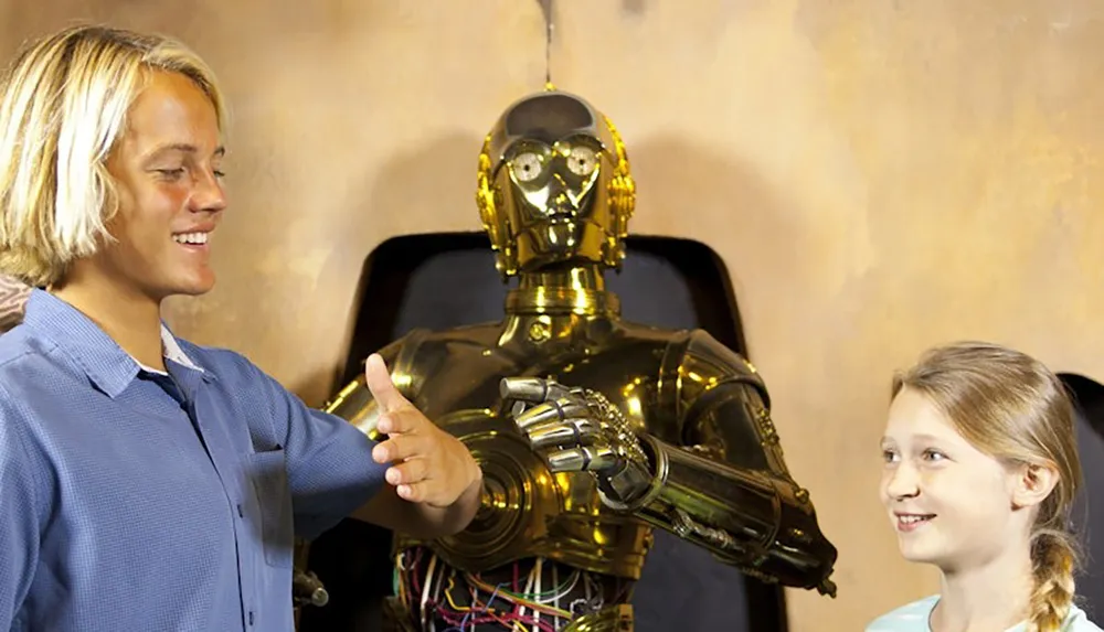 A young boy and girl are interacting with a golden humanoid robot