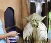 Three people are smiling and posing with figures of Yoda and R2-D2 from Star Wars