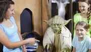 Three people are smiling and posing with figures of Yoda and R2-D2 from Star Wars.