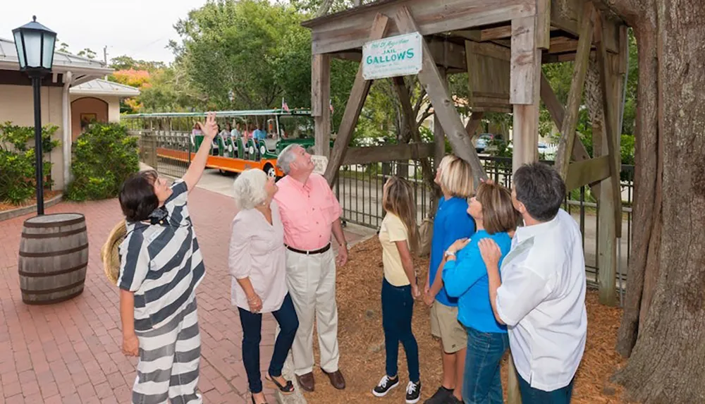 A group of people is looking up at a wooden gallows structure with a sign that reads Jail Gallows