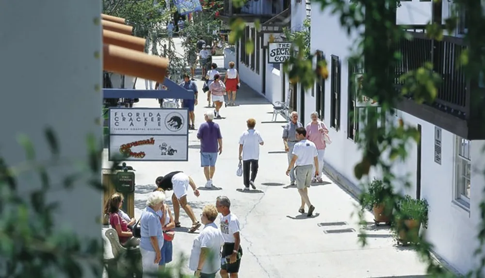 People are strolling down a busy outdoor walkway lined with shops and cafes including one named Florida Cracker Cafe