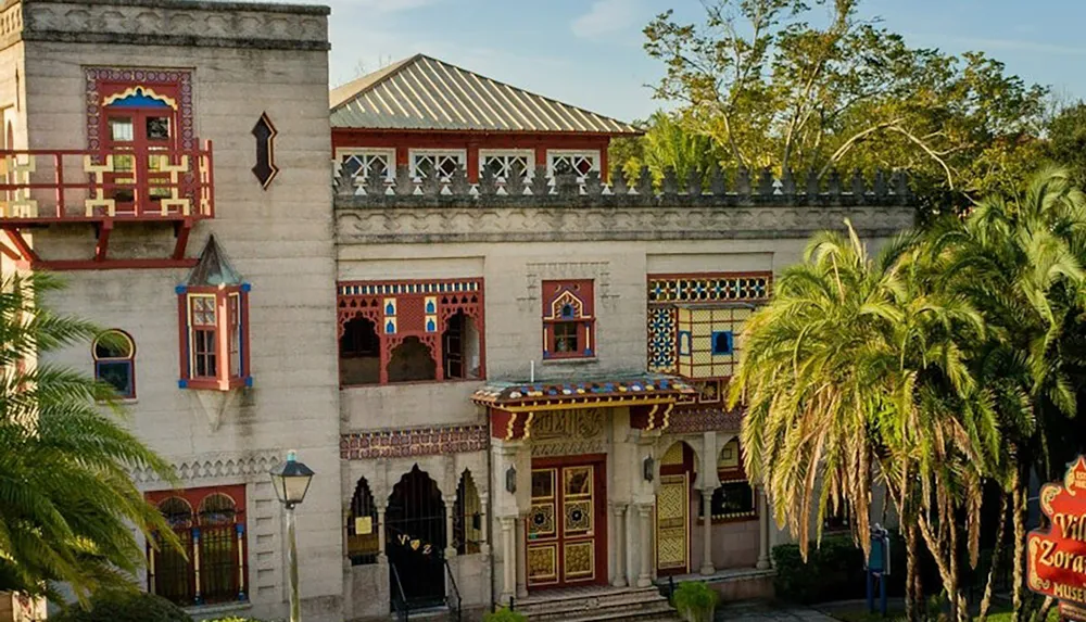 The image depicts a colorful and ornate building with intricate designs palm trees and a sign partially visible in the foreground