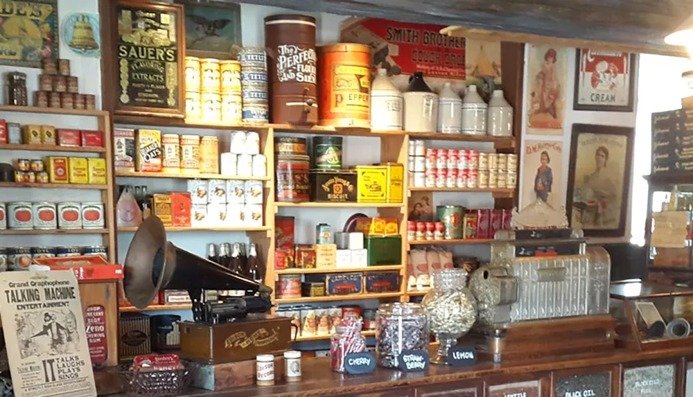 The image depicts a vintage general store interior featuring shelves stocked with old-fashioned products canned goods jars advertisements and a gramophone