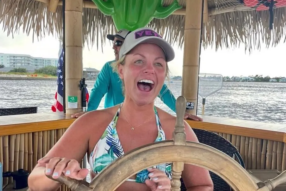 A joyful woman is steering a boat with a thatched roof structure expressing excitement or happiness while someone stands behind her