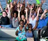 A group of people is enjoying a ride in a bright green shark-themed tour boat on a calm body of water