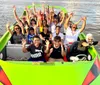 A group of people is enjoying a ride in a bright green shark-themed tour boat on a calm body of water