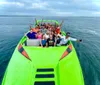 A group of people is enjoying a ride on a vibrant green speedboat with shark teeth graphics painted on the bow