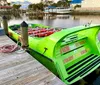 A group of people is enjoying a ride on a vibrant green speedboat with shark teeth graphics painted on the bow