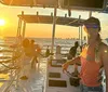 A group of people are enjoying a sunset cruise on a boat with a view of the distant city skyline