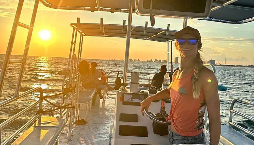 A group of people are enjoying a sunset cruise on a boat with a view of the distant city skyline