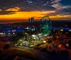 A silhouette of a Ferris wheel stands against a vibrant sunset over the ocean