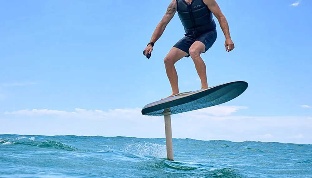 A person is riding an eFoil board above the waters surface under a blue sky