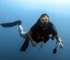 A diver with a prosthetic leg is swimming underwater equipped with fins a diving mask and a snorkel