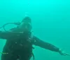 A diver is gesturing underwater surrounded by a greenish-blue aquatic environment