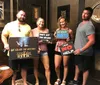 Four people are posing with humorous signs indicating their different experiences after solving an escape room challenge themed around a stolen relic