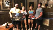 Four people are posing with humorous signs indicating their different experiences after solving an escape room challenge themed around a stolen relic.