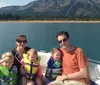 A family of two adults and three children is enjoying a sunny day on a boat with a scenic mountainous backdrop