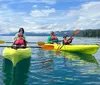 A person in a white sun hat is kayaking on a shimmering body of water surrounded by a forested area