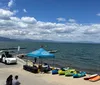 A group of people are enjoying paddleboarding and kayaking on a sunny day on a clear body of water with mountains in the background