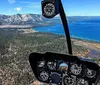 The image shows a helicopters cockpit view with instrumentation in focus overlooking a panoramic landscape of a lake mountains and forests