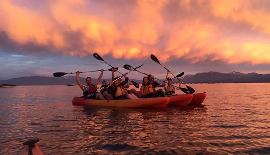 A group of people are kayaking on calm waters under a vividly colored sunset sky.