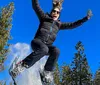 A person is captured mid-jump with a joyful expression against a clear blue sky backdrop with snow scattering from their boots