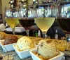 The image shows an assortment of different colored ice creams in small square bowls presented with three glasses of wine capturing a pairing of desserts and drinks