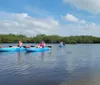 Three individuals are kayaking on a body of water with a focus on the person closest to the camera who is smiling
