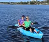 Two people are smiling and enjoying a sunny day out on the water in a blue tandem kayak