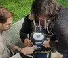 Two people are attentively examining an electronic device outdoors