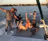 A group of people are joyfully posing on a boat during what appears to be a sunset sailing trip