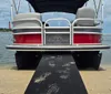 A pontoon boat is docked on a sandy shore under a blue sky with scattered clouds