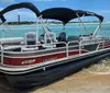 A pontoon boat is docked on a sandy shore under a blue sky with scattered clouds