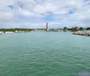 A pontoon boat is docked on a sandy shore under a blue sky with scattered clouds